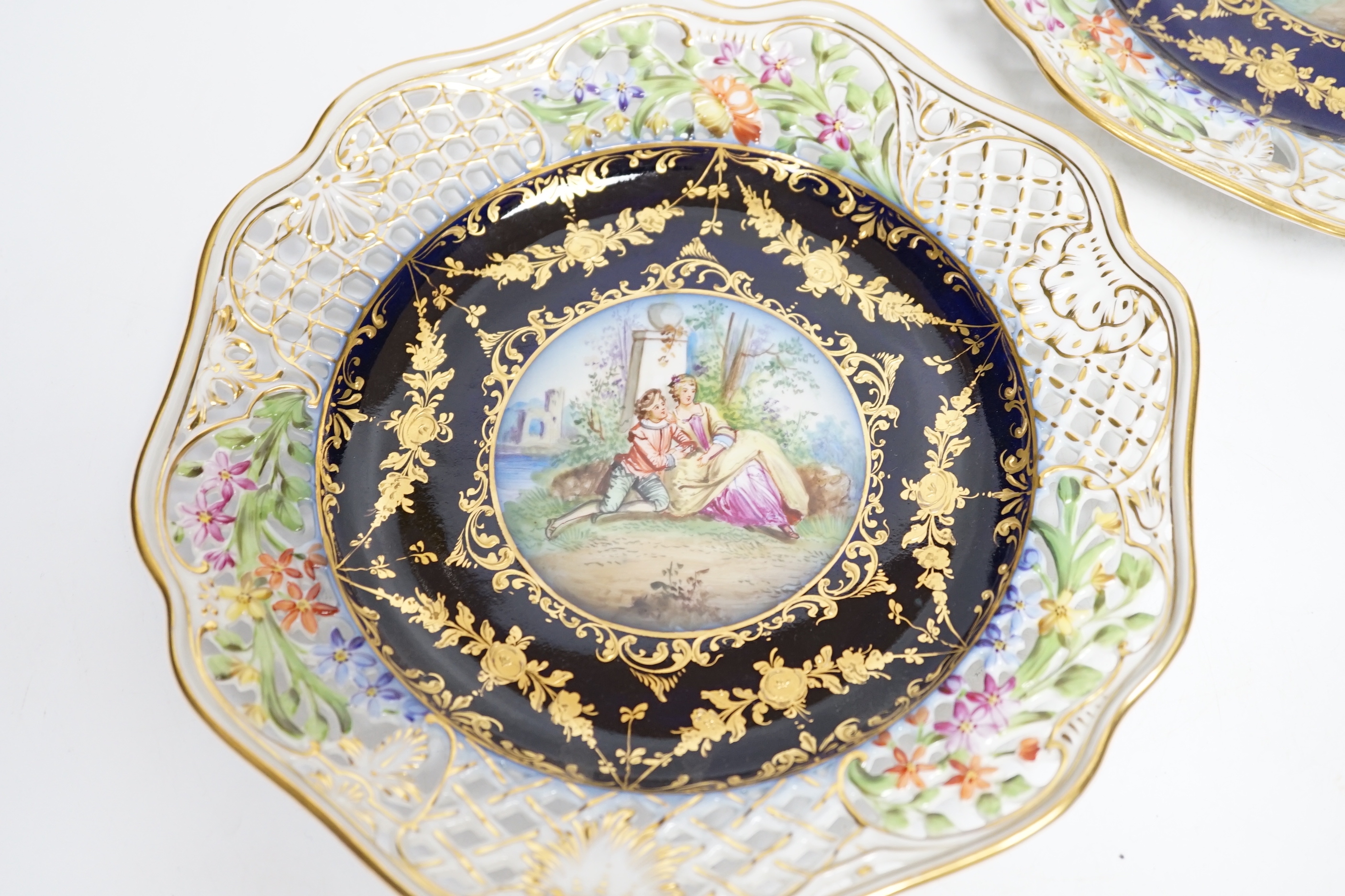 A pair of Dresden blue cabinet plates decorated with central cartouche of lovers, 22cm diameter